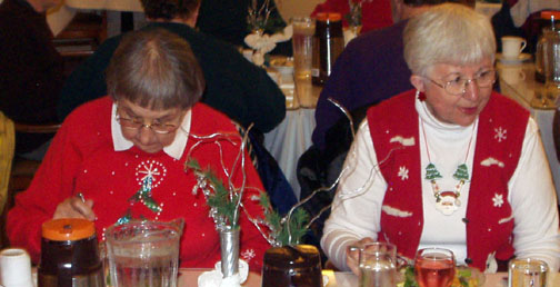 Shirley and Dottie sitting at their table wearing bright red sweaters